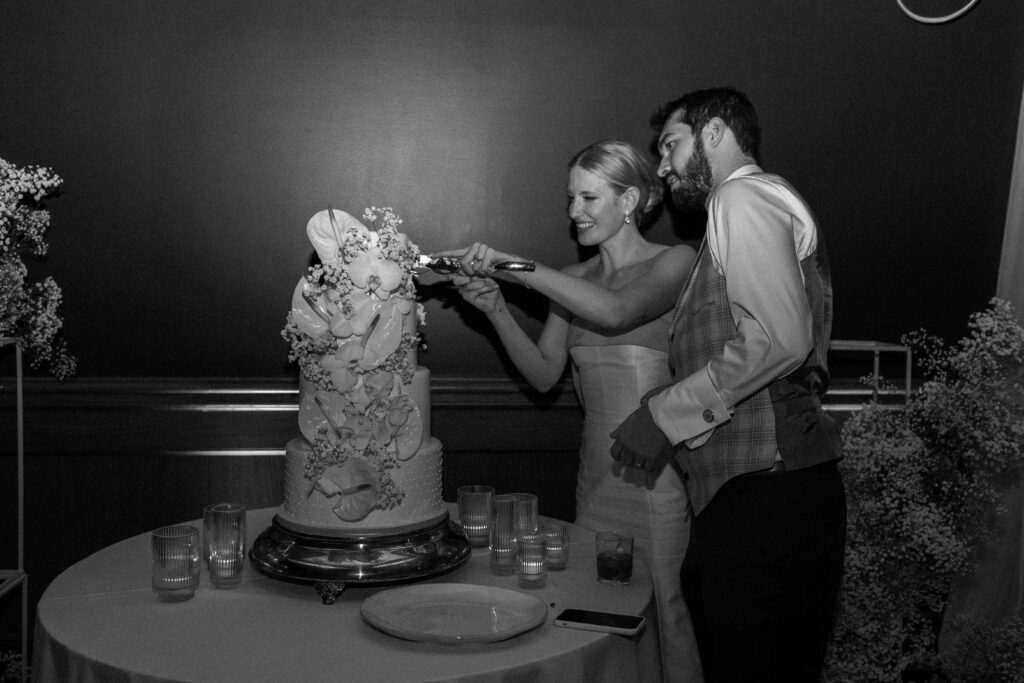 Bride and groom cut their orchid-inspired cake at Vauxhall The Ramble Hotel in Denver for their reception.