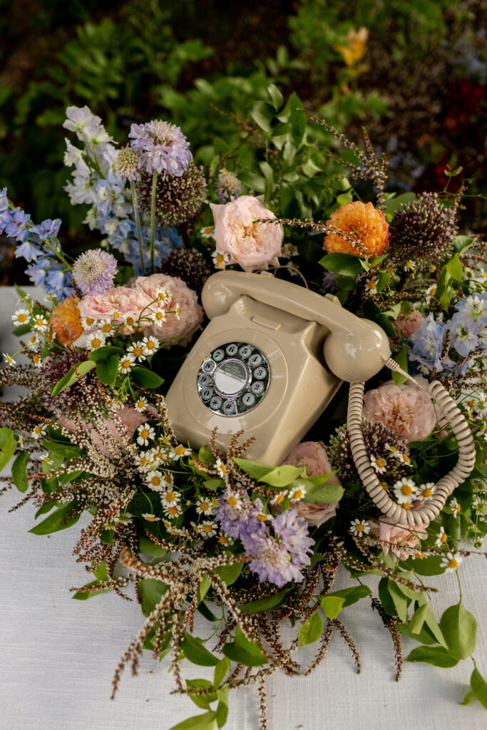 Fun details like a phone to leave the bride and groom messages arranged in a bed of flowers.