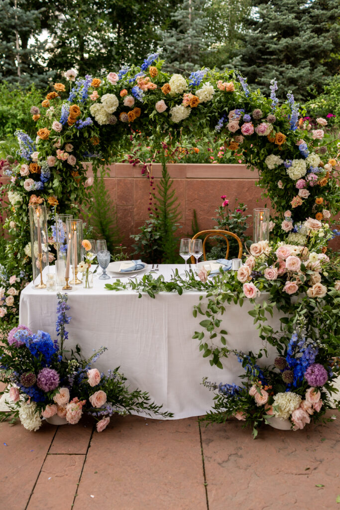 Table is set for dinner at the Denver Botanic Garden Wedding with a stunning floral arch.