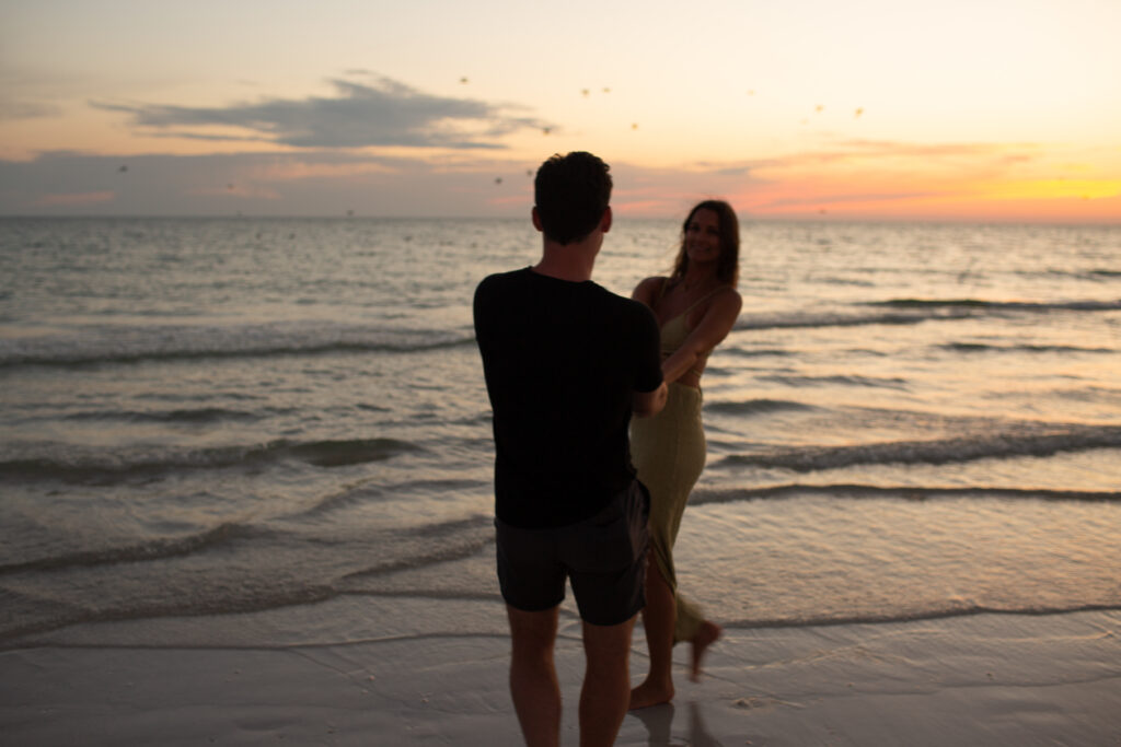 happy couple holding hands during sunset at the ocean in florida