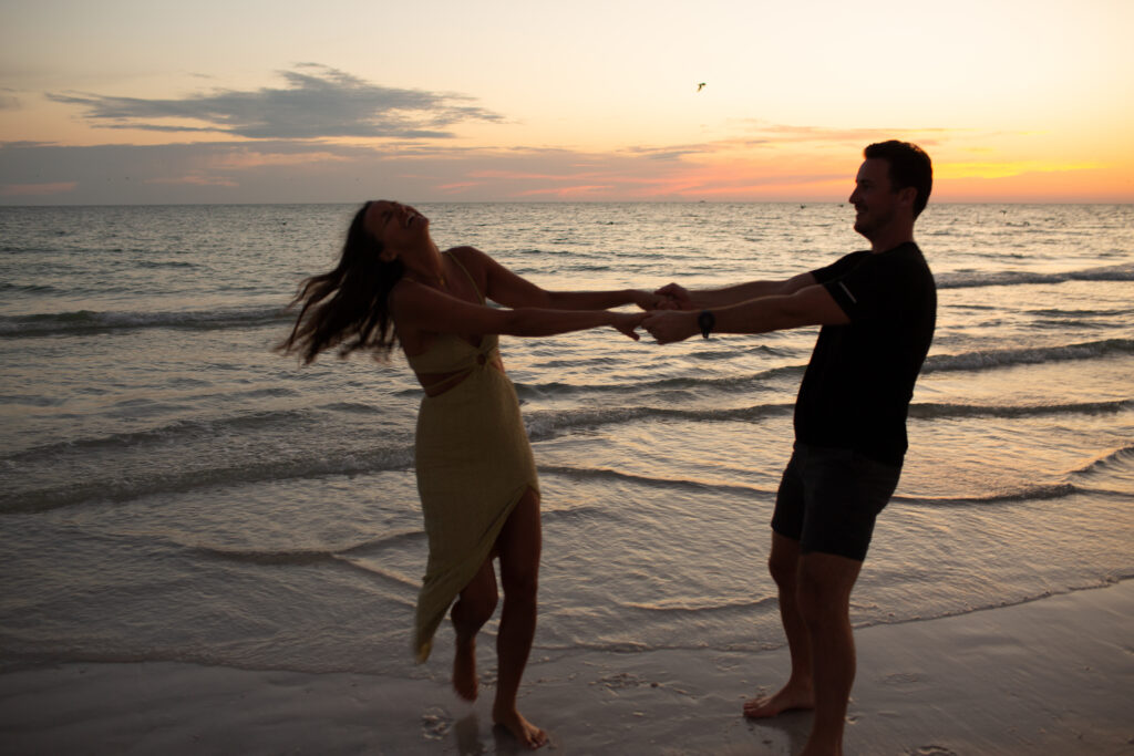 couple laughing and twirling around at the beach