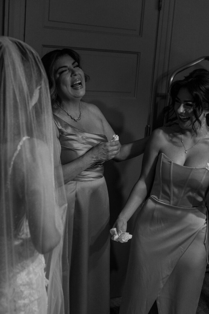 mom and sister and bride laughing while getting ready for wedding