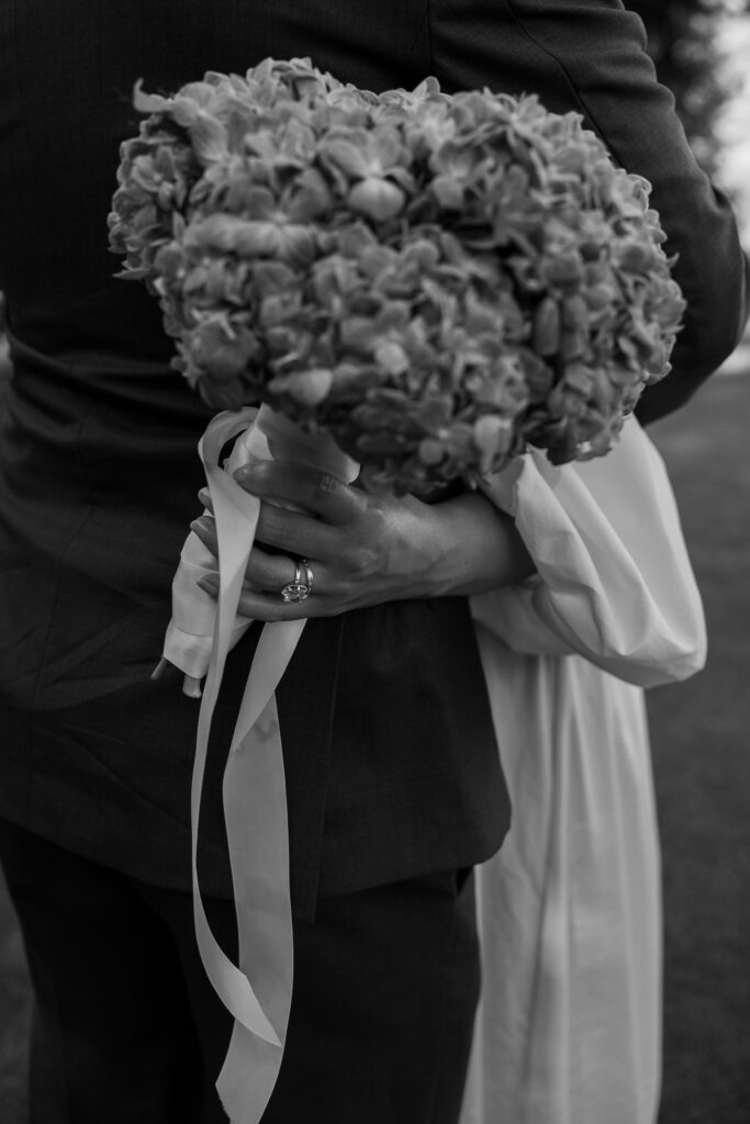 Close-up of bride holding a large green hydrangea bouquet behind groom at their luxury California wedding.