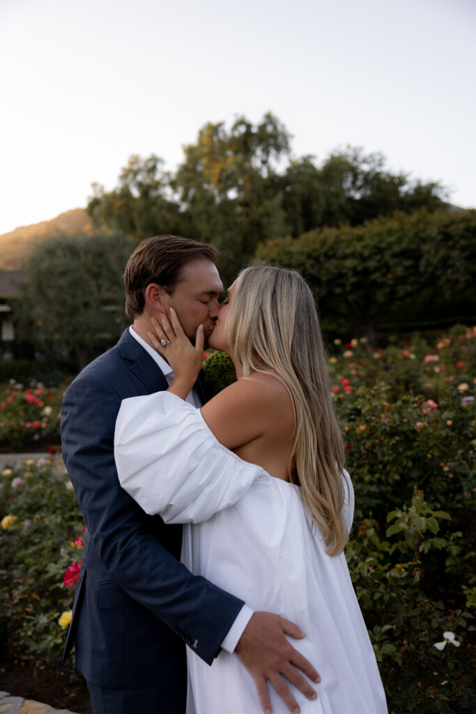 Bride and groom share a sunset kiss in a lush garden at a luxury California estate wedding.