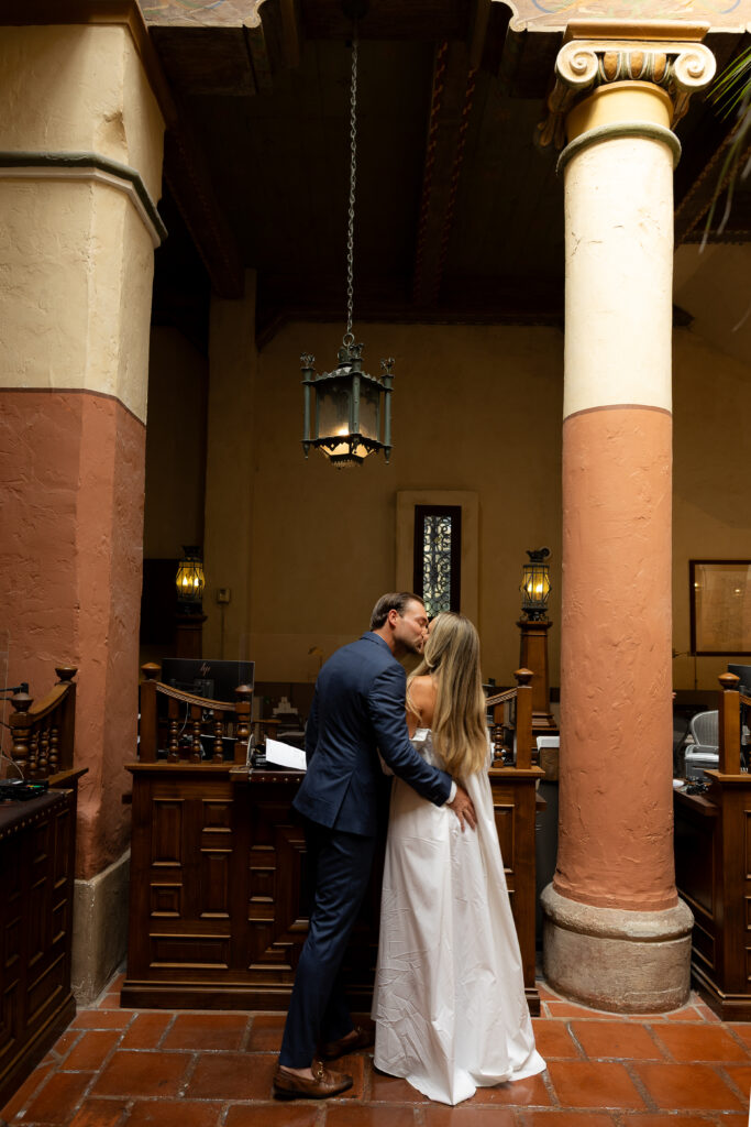 Bride and groom signing wedding documents inside a historic Spanish-style villa with terracotta floors and exposed wood beams during their luxury California estate wedding.