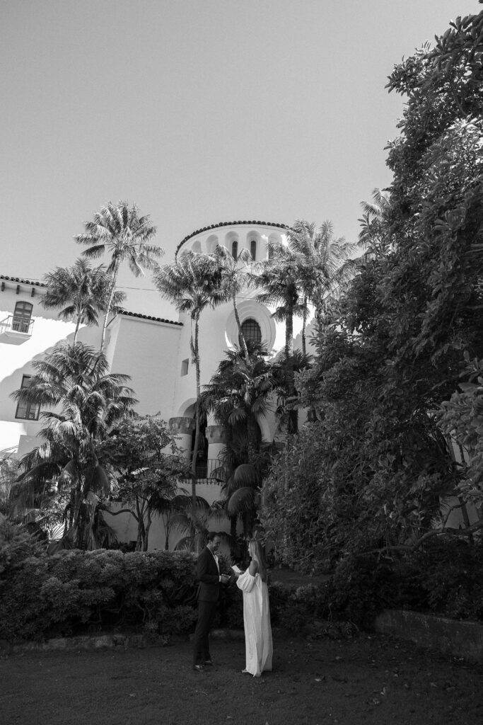 Bride and groom exchange vows under a towered villa with palm trees at a luxury California estate wedding in San Ystrido