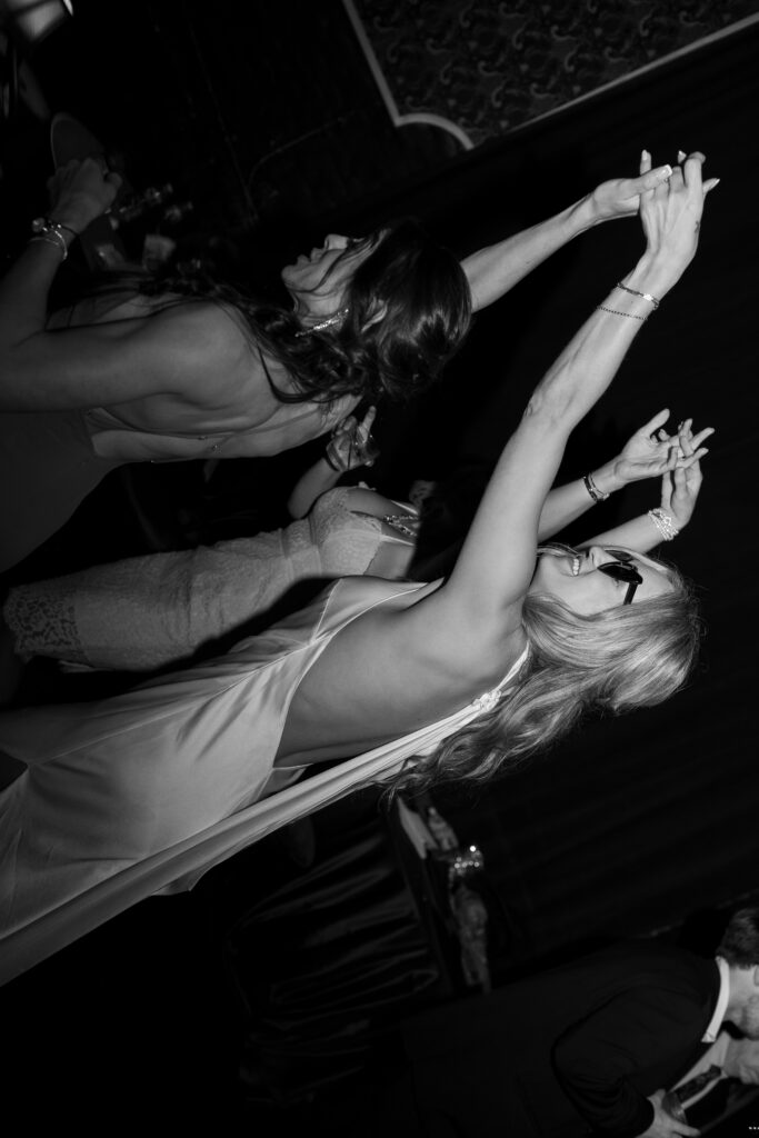 The moments of a dance floor- The bride is wearing her heart shaped sunglasses while holding the hands in dancing with her friends in celebration of the marriage!