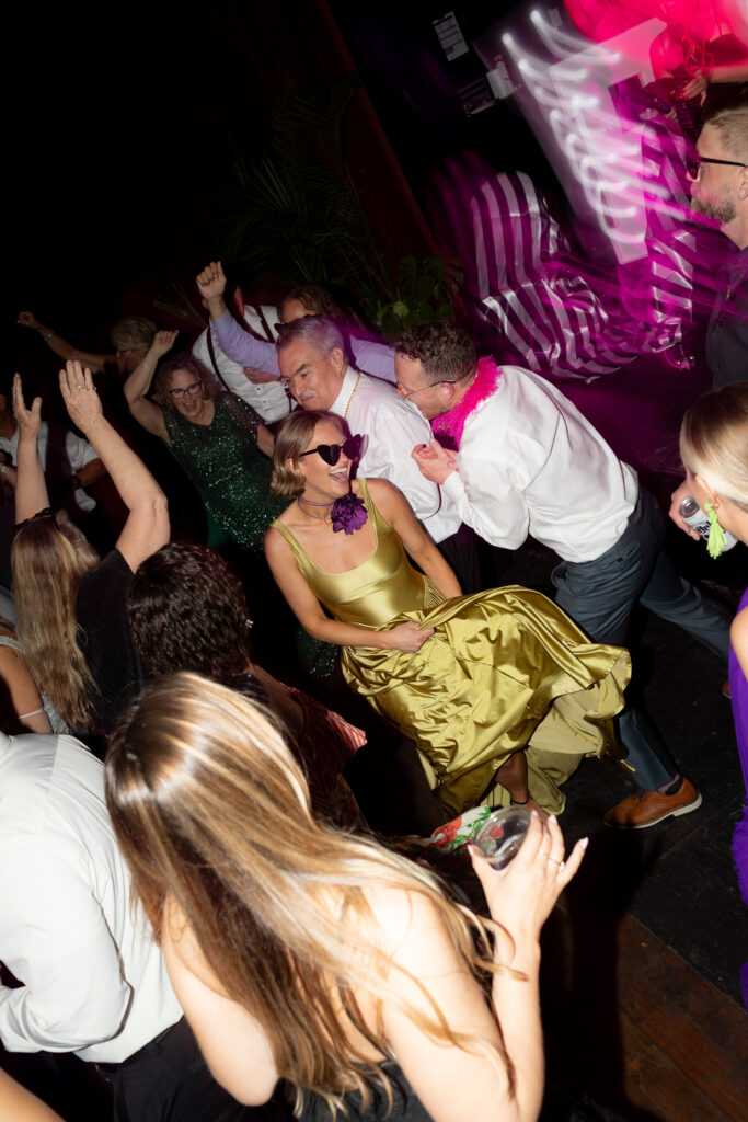 Lights blurred, the wedding guests dance boldly on the dance floor with the newlyweds, sharing laughter and smiles.