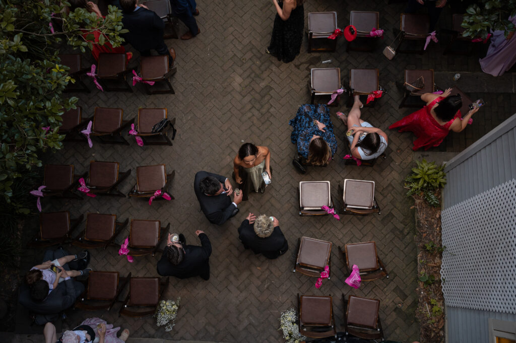 An arial photo of the ceremony chairs slowly being filled by guests. People are chatting in light conversation and laughter as they find their seats. Linden Wilson specializes in the hidden moments of luxury photography.