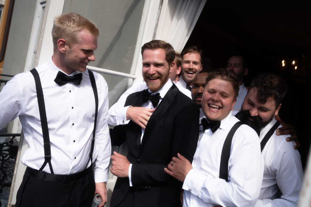 Groomsmen all holding onto the groom in wedding party photo.