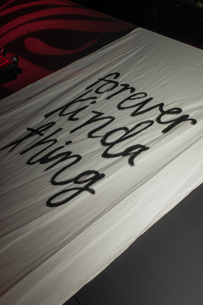 "Forever kinda thing" painted in black on a large white drape done by the bride is showcased in the afterparty of the wedding.