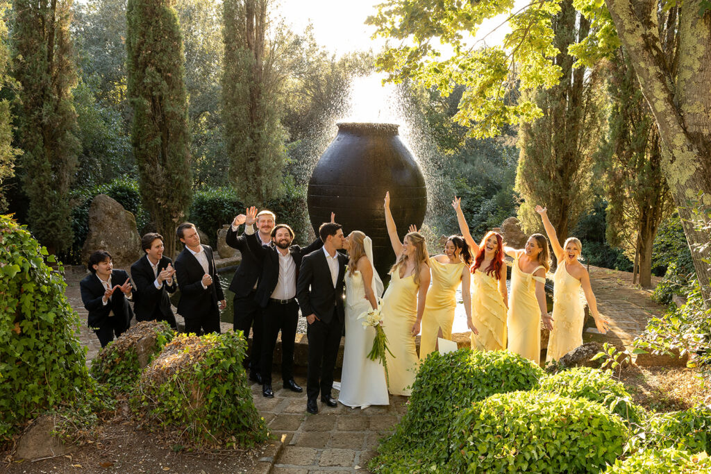 bridal party celebrates as bride and groom kiss