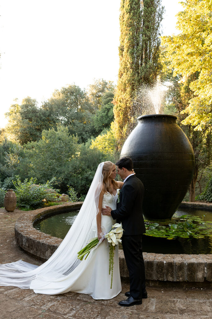 bride and groom share an intimate moment at the fountain after their italy wedding ceremony