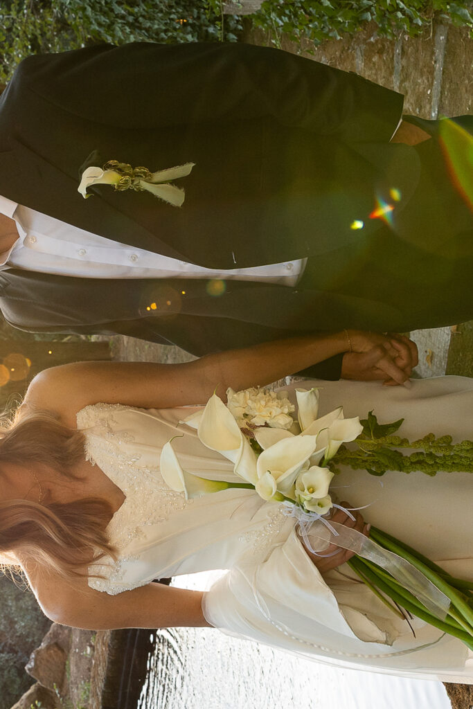sun shining through bride and groom as they hold hands