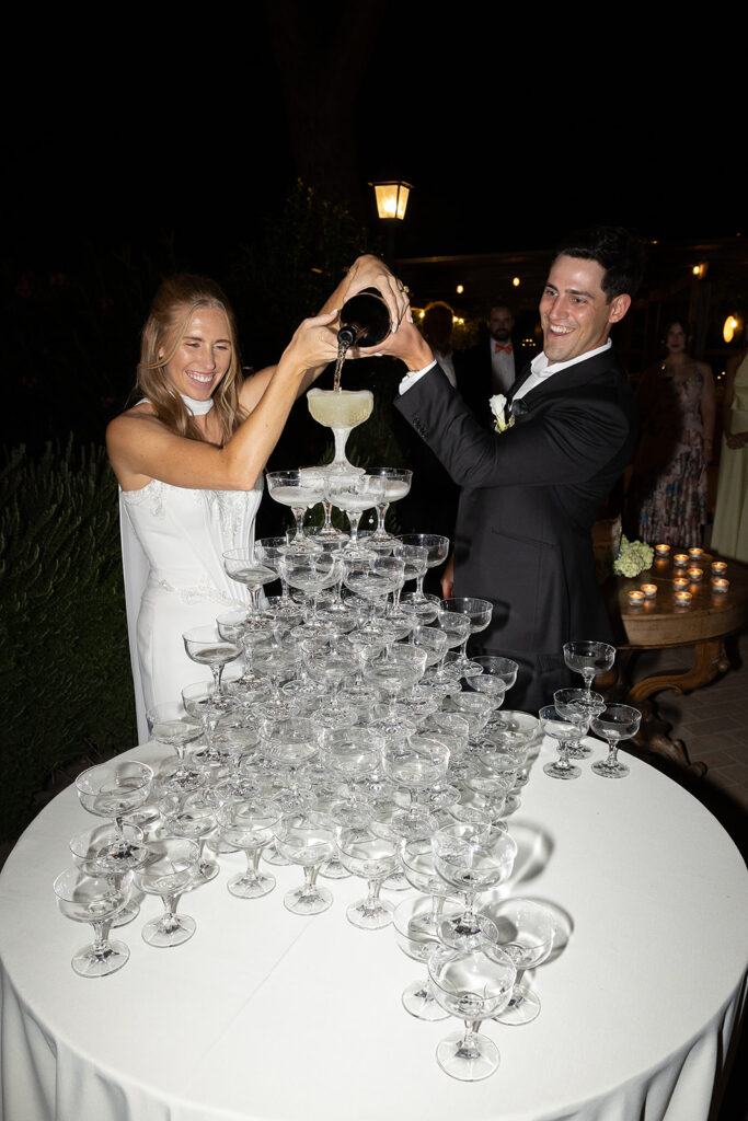 bride and groom pouring a champagne tower at their italy wedding reception