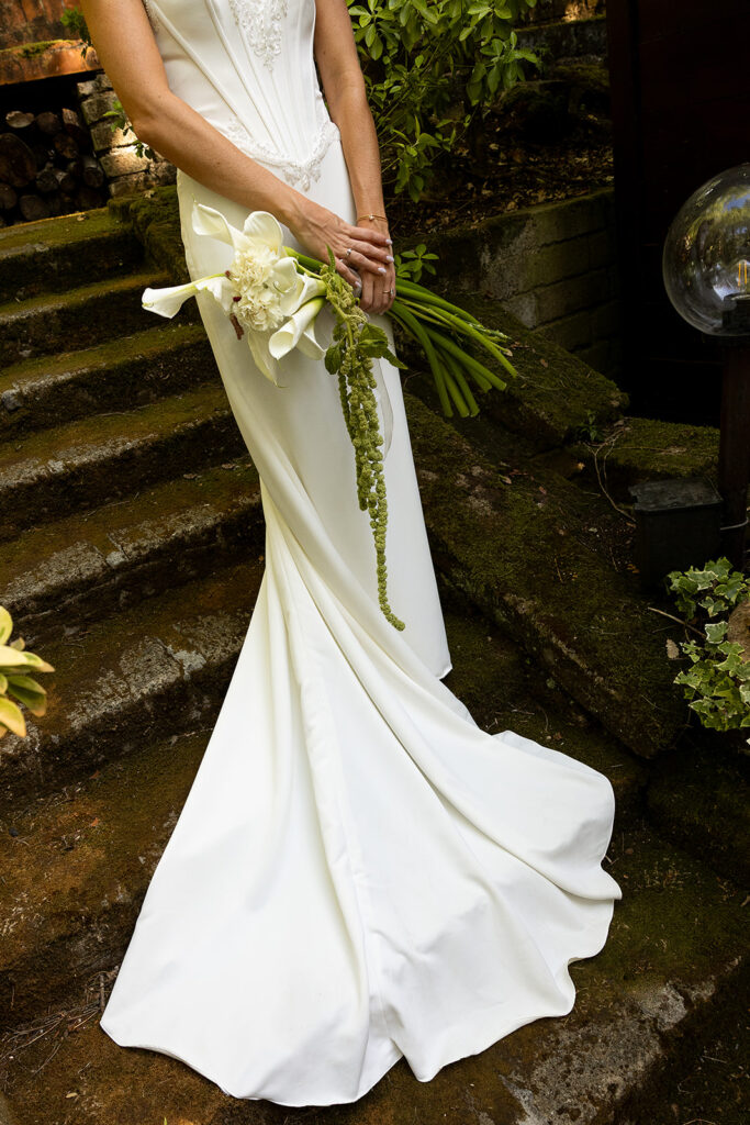 dress details with simple bouquet standing on the mossy steps