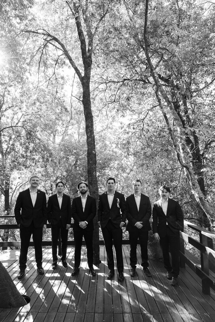 grooms and groomsmen pose for bridal party photo